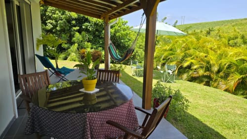 Terrasse du jardin de la Villa Tourmaline avec table à manger, hamac, plantes tropicales et jardins luxuriants au Lorrain