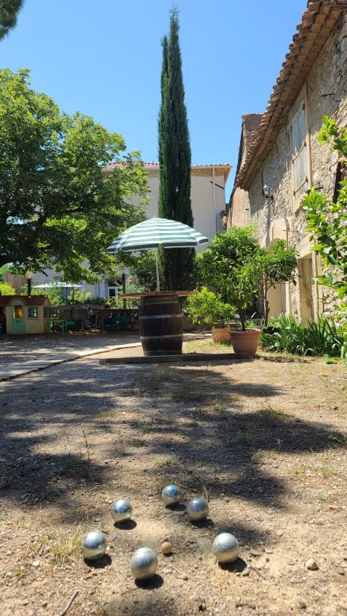 Boules de pétanque dans la cour de la maison d'hôtes Le N°9 à Argeliers avec parasol et cyprès