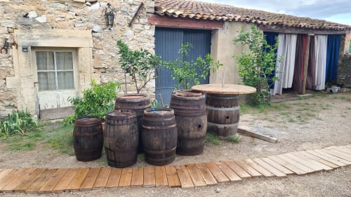 Cour aménagé avec des tonneaux de vin rustiques  Le N°9 à Argeliers, France, avec bâtiments en pierre et cour intérieure.les appellations viticoles sont le Minervois, st chinian, corbière.