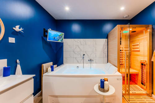 Luxury bathroom with blue walls, jacuzzi tub, marble tiles, sauna, and wellness amenities at Wellkhome Bordeaux