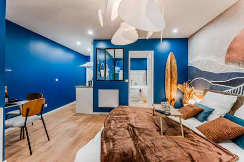 Modern blue bedroom with wooden accents, surfboard decor, and spa amenities at Wellkhome Bordeaux