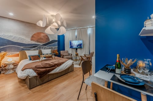 Luxury apartment bedroom in Bordeaux with blue accents, modern furnishings, and city view overlooking a ship