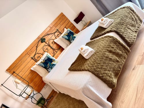 Quarto aconchegante na Kindnessmoon B&B, Óbidos Portugal, com cama branca, mantas verde oliva e cabeceira de madeira decorativa