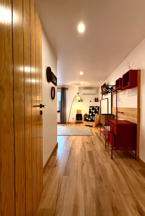 Corredor de quarto moderno com piso em madeira, camas beliche vermelhas e guarda-roupa revestido em Kindnessmoon, Óbidos, Portugal