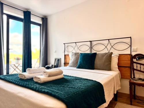 Quarto luminoso na Kindnessmoon em Óbidos com vista para a cidade, detalhes em azul-esverdeado e comodidades modernas