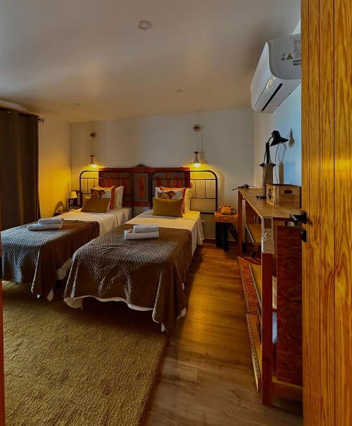 Duas camas com estrutura de madeira no quarto Laranjeira das Loiras da pousada Kindnessmoon, Óbidos Portugal, com ar condicionado e design moderno