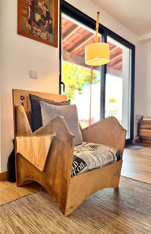 Wooden armchair with cushions in Kindnessmoon cottage, Óbidos, with yellow pendant lamp and glass doors to terrace