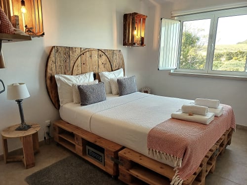 Rustic wooden bed with white linens and pillows in villa bedroom at Kindnessmoon, Obidos Portugal