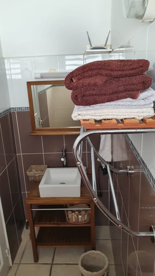 Salle de bain avec serviettes empilées bordeaux et blanches au Nid De Bellemont, Trois-Rivières