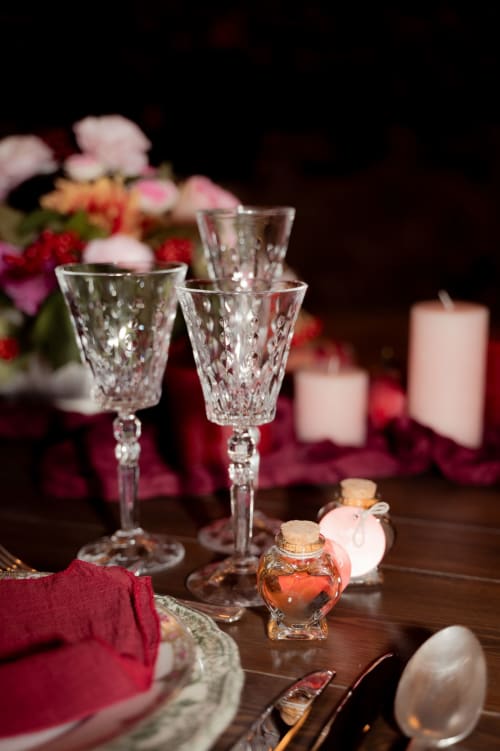 Elegant table setting at Domaine du Tertre Ychot with crystal glasses, burgundy napkins, flowers, and candles.