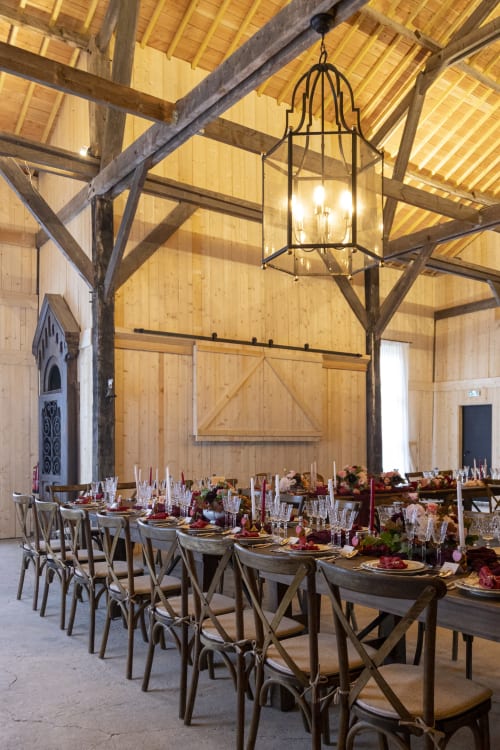 Elegant barn reception at Domaine du Tertre Ychot with wooden beams, long tables, and rustic decor in Dol de Bretagne,
