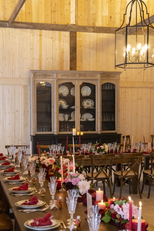 Elegant dining room at Domaine du Tertre Ychot with floral centerpieces, candlelit table settings, and antique display