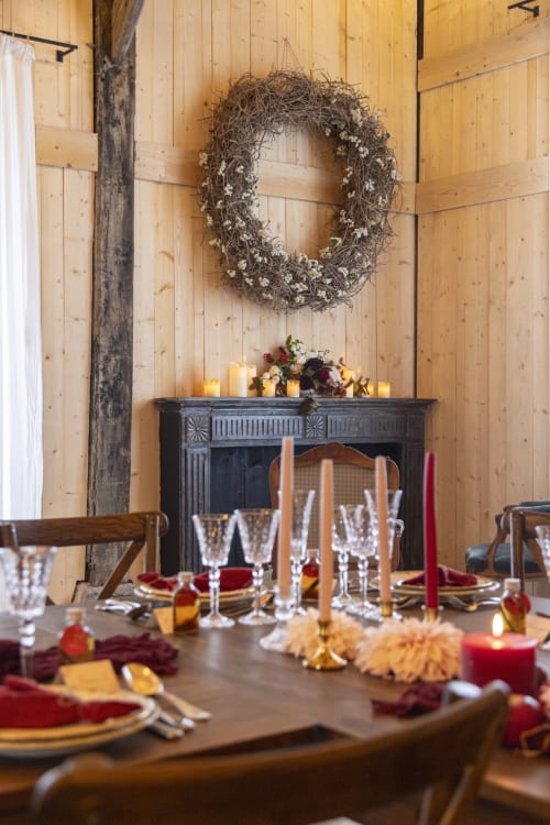 Rustic dining room at Domaine du Tertre Ychot with festive table setting, wreath above fireplace, candles and burgundy