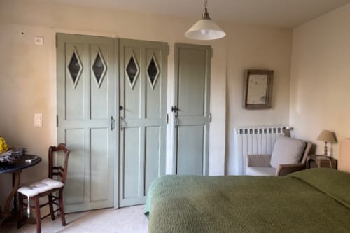 Bedroom with green bedspread, vintage wardrobe, radiator, and pendant light at Ancienne Maison des Gardes B&B apartment in
