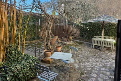 Charming courtyard garden at Ancienne Maison des Gardes in Lourmarin with seating, plants, and umbrella shade