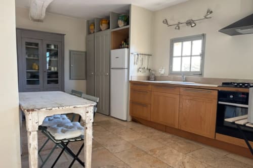 Spacious kitchen in Lourmarin apartment with wooden cabinetry, stainless steel appliances, and marble countertops