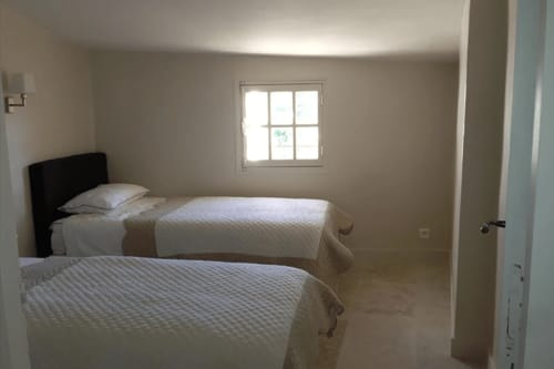 Spacious bedroom at Ancienne Maison des Gardes in Lourmarin with two beds, window, and bright natural light
