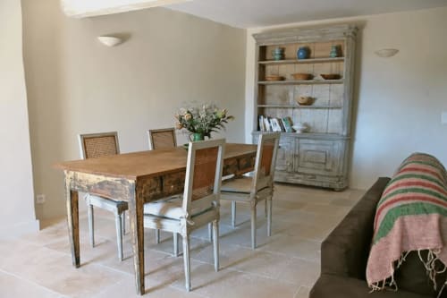 Dining area in Lourmarin apartment with wooden table, rattan chairs, blue hutch, sofa, and terrace access
