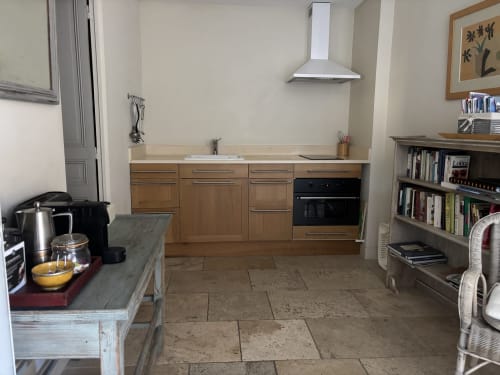 Spacious kitchen at Ancienne Maison des Gardes in Lourmarin with wooden cabinets, modern oven, and terracotta tile flooring