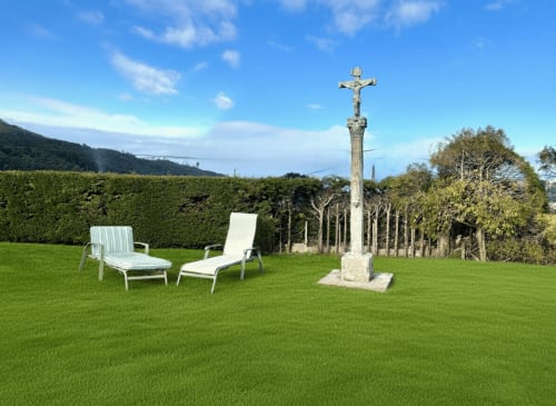 Amplio jardín con tumbonas y cruz de piedra en la casa de MarySol en Baiona, España