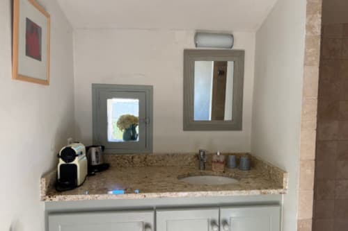 Bathroom vanity with granite countertop, dual mirrors, and amenities in Lourmarin bed & breakfast room