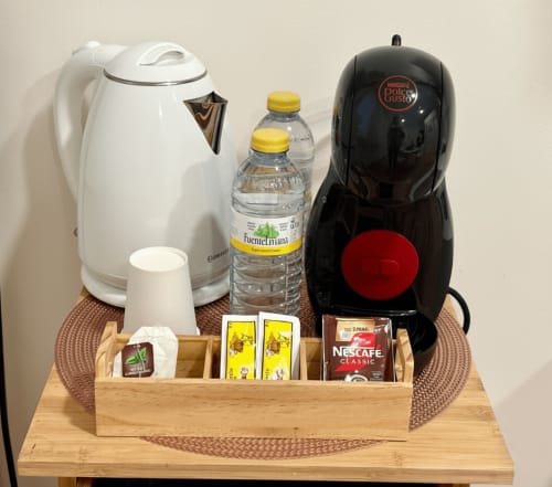 Estación de café en el apartamento Ruliña de Holibai Baiona con hervidor, cafetera Dolce Gusto, botellas de agua y Nescafé