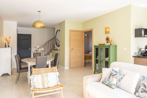 Modern villa living area in Favone with dining table, cream sofa, green storage cabinet, and open layout connecting to, managed by Corsu di Core conciergerie