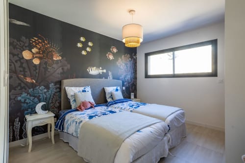 Modern bedroom in Villa Oia , Favone, with blue ocean-themed wall mural, comfortable bed, and natural light, managed by Corsu di Core