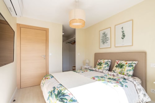 Bright bedroom in Villa Oia , Favone, with tropical bedding, beige headboard, and botanical wall art, managed by Corsu di Core