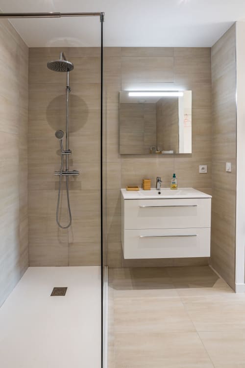 Modern bathroom in Villa Oia with rainfall shower, white vanity, and beige tile, managed by Corsu di Core