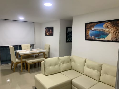 Moderna sala de estar en Olamar Living, Coveñas, con sofá seccional crema, mesa de comedor y cuadros enmarcados
