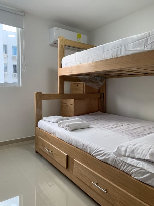 Camas literas de madera con sábanas blancas y toallas enrolladas en una luminosa habitación de Olamar Living, Coveñas