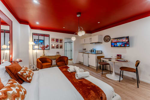 Red-accented studio apartment in Bordeaux with twin beds, orange chairs, kitchenette, and modern amenities