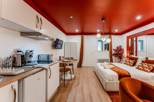 Wellkhome Red Apartment in Bordeaux with open kitchen, dining area, and bed featuring modern red ceiling and white
