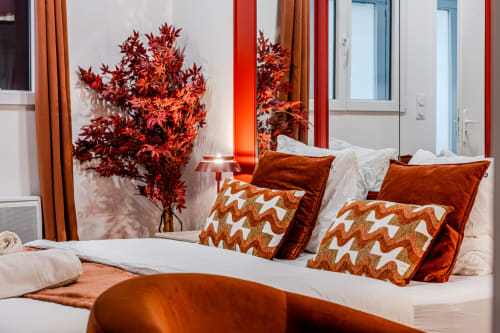 Modern bedroom at Wellkhome Bordeaux with red autumn décor, velvet pillows, patterned cushions, and decorative dried plant