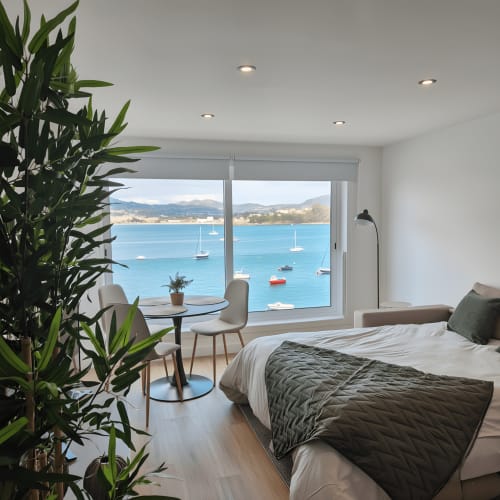Lujosa habitación frente al mar en Baiona con vistas espectaculares, mobiliario moderno y vistas de veleros a través de grandes ventanales