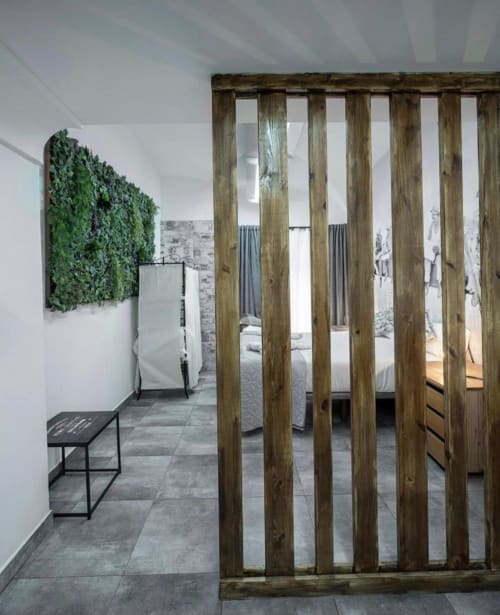 Apartamento moderno en Mérida con biombo de madera, pared verde con plantas y dormitorio de diseño contemporáneo