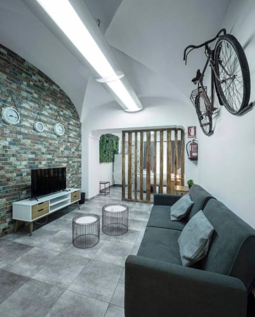 Sala de estar moderna en Mérida con ladrillo expuesto, sofá gris, bicicleta montada en pared y vistas de la ciudad