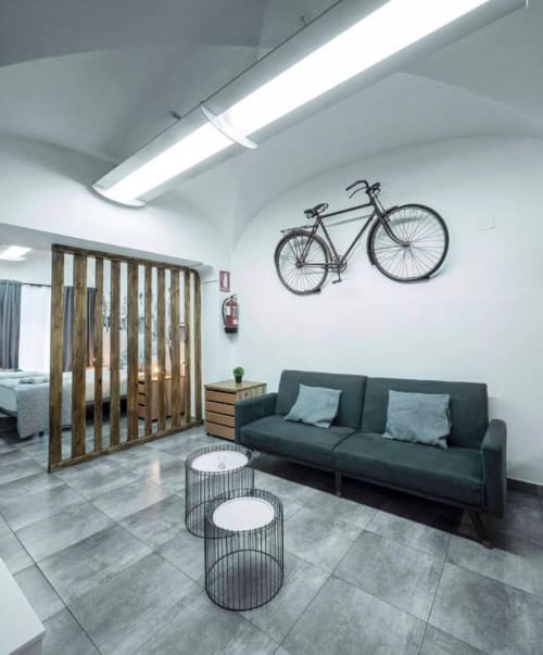 Sala de estar de apartamento moderno en Mérida con sofá oscuro, mesas auxiliares geométricas y arte de bicicleta en la pared