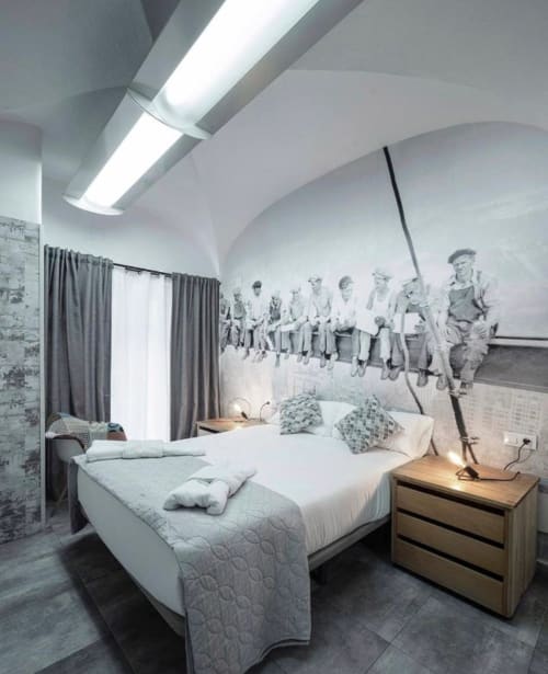 Dormitorio moderno en apartamento Gestyp-AT de Mérida con cama blanca, mesita de madera y mural vintage en techo curvo.