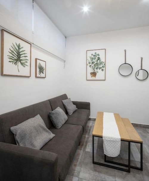 Sala moderna en Mérida con sofá gris, mesa de madera y arte botánico en la pared