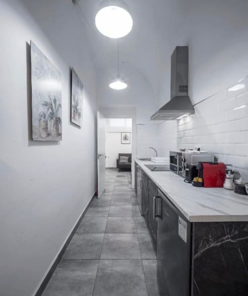 Cocina tipo galera moderna en departamento de Mérida con azulejos blancos metro, muebles oscuros y campana extractora acero inoxidable