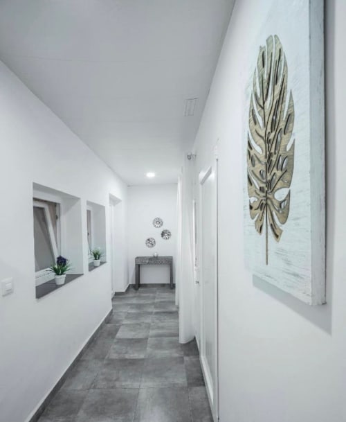 Pasillo moderno con paredes blancas, piso de cerámica gris y decoración de hojas botánicas en el apartamento Gestyp-AT de Mérida