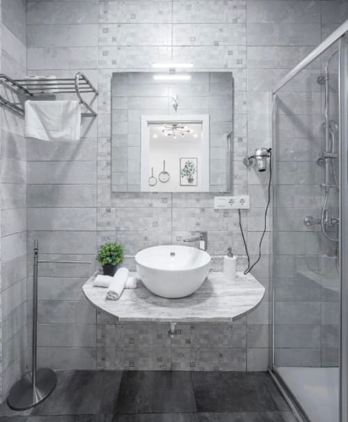 Baño moderno con lavabo blanco tipo vessel, paredes con azulejos grises y cabina de ducha en el apartamento Gestyp-AT de Mérida