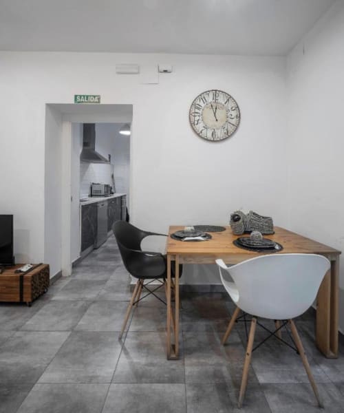 Comedor moderno en apartamento de Mérida con mesa de madera, sillas contrastantes y acceso a cocina señalizado con letrero verde SALIDA