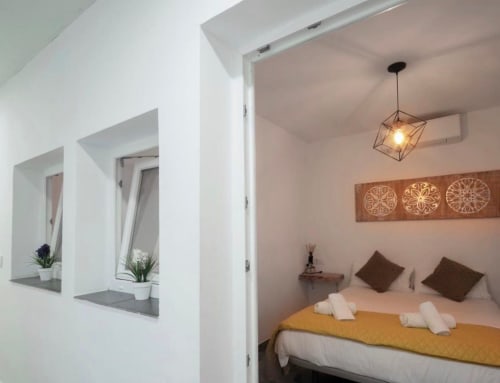 Dormitorio moderno en apartamento de Mérida con cama queen, lámpara colgante, arte decorativo en pared y estanterías integradas con plantas