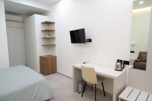 Camera d'hotel moderna a Museo19 a Napoli con letto, scrivania, TV a parete, scaffalatura in legno e specchio