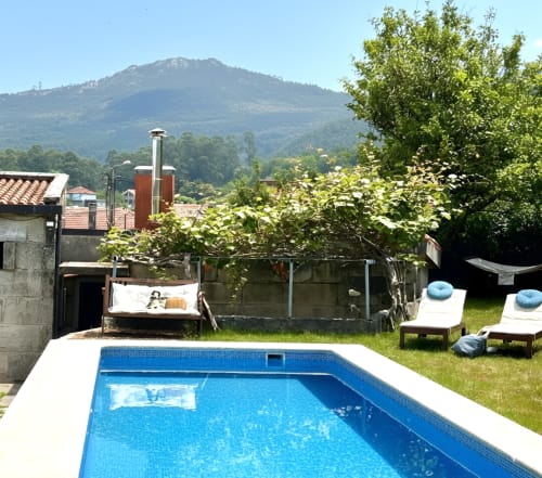 Jardín de la Casa Celso con piscina azul, tumbonas y vistas a la montaña cerca de Baiona, España