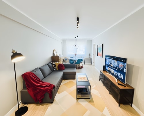 Sala de estar moderna del apartamento de Baiona con sofá gris, televisor, comedor 