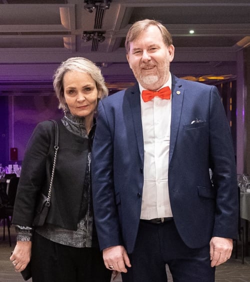 Deux invités en tenue de soirée à l'événement Conciergerie Saint Martin Paris, élégant lieu aux éclairages violets